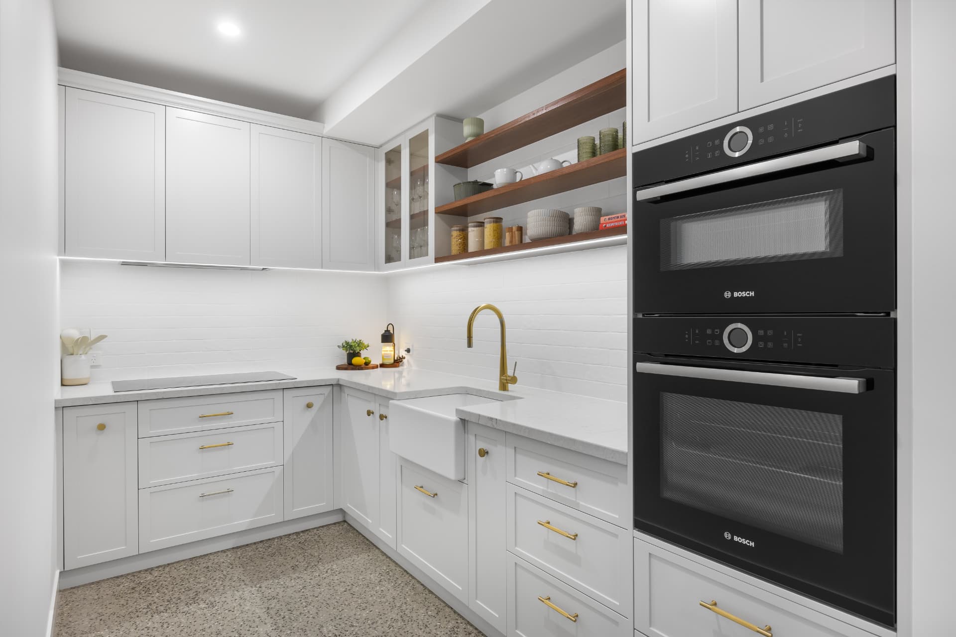 White butler's pantry display with brass tapware and Bosch ovens